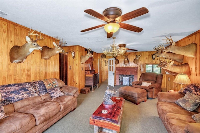 living room with wooden walls, ceiling fan, a fireplace, a textured ceiling, and light colored carpet