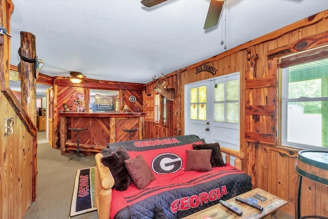 bedroom with carpet flooring, wooden walls, and ceiling fan