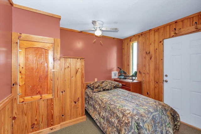 carpeted bedroom with ceiling fan, crown molding, and wooden walls