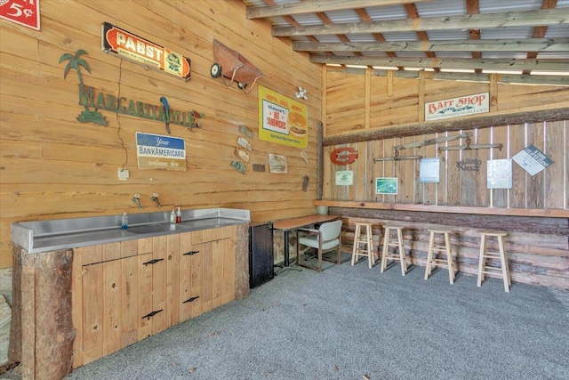 miscellaneous room with light carpet, wooden walls, and lofted ceiling with beams