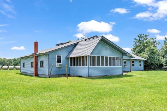 rear view of property featuring a lawn, a sunroom, and cooling unit