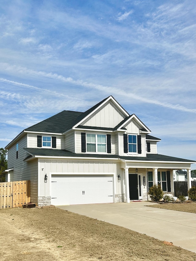 view of front of home featuring a garage, concrete driveway, stone siding, fence, and board and batten siding