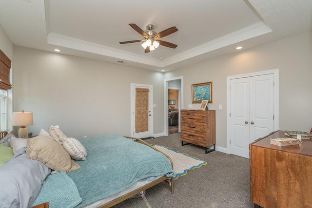 bedroom with ornamental molding, a raised ceiling, and dark colored carpet