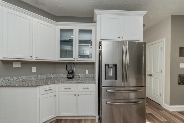 kitchen with white cabinetry, stainless steel fridge, light stone countertops, and dark hardwood / wood-style floors