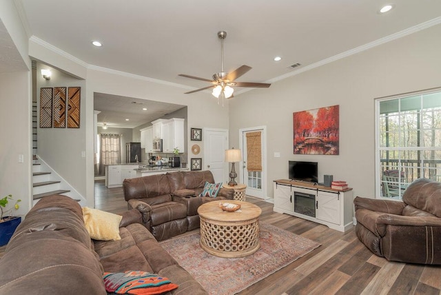 living room featuring dark wood-type flooring, ornamental molding, and ceiling fan