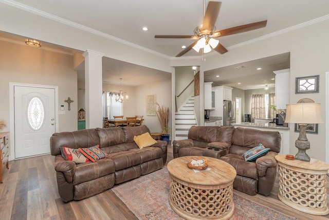 living room with decorative columns, ornamental molding, dark hardwood / wood-style floors, and ceiling fan with notable chandelier