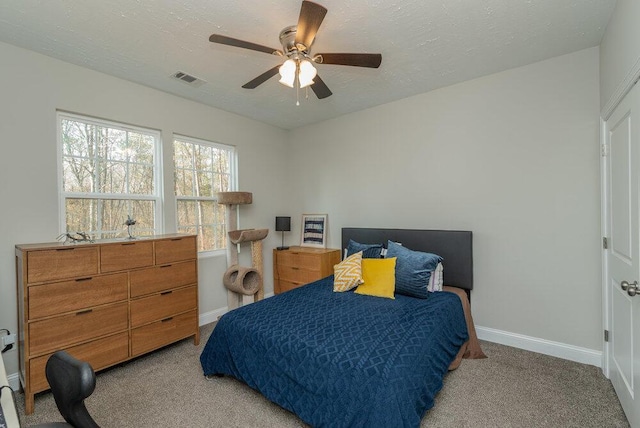 carpeted bedroom featuring ceiling fan and a textured ceiling