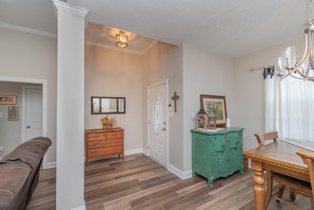 entryway featuring crown molding, a chandelier, a textured ceiling, dark hardwood / wood-style flooring, and decorative columns