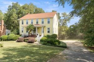 colonial-style house featuring a front lawn