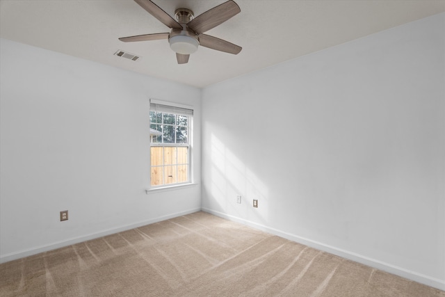 carpeted spare room featuring visible vents, baseboards, and ceiling fan