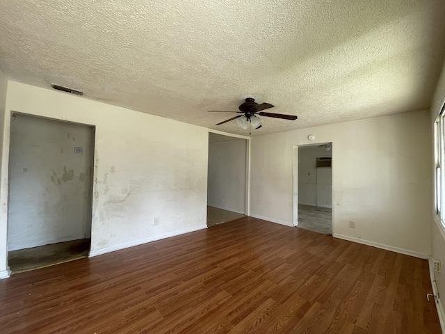 spare room featuring a textured ceiling, wood finished floors, visible vents, a ceiling fan, and a wall mounted air conditioner