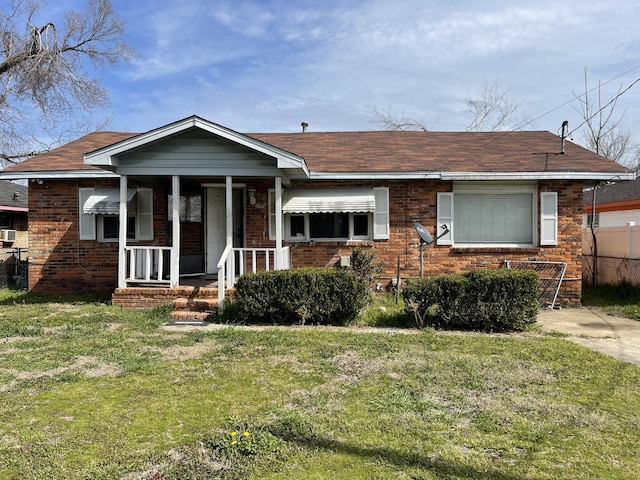 bungalow with a front yard, fence, a porch, and brick siding