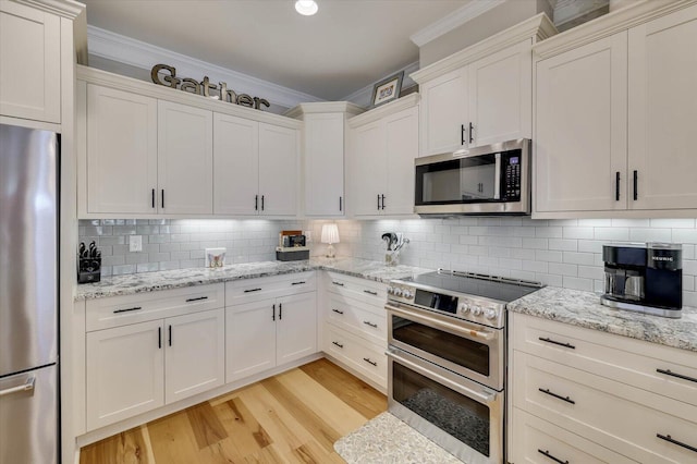 kitchen with decorative backsplash, appliances with stainless steel finishes, light hardwood / wood-style floors, and white cabinetry