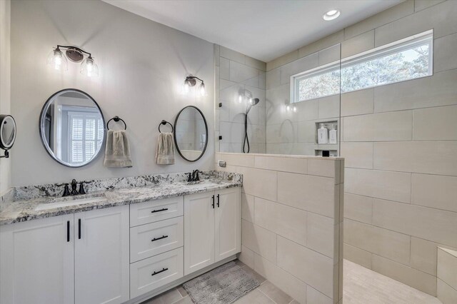 bathroom with tile patterned floors, vanity, and a tile shower