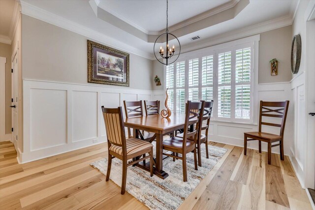 dining area with light hardwood / wood-style floors, an inviting chandelier, a healthy amount of sunlight, and crown molding