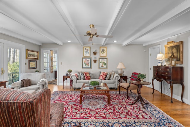 living room with baseboards, beam ceiling, wood finished floors, and a ceiling fan