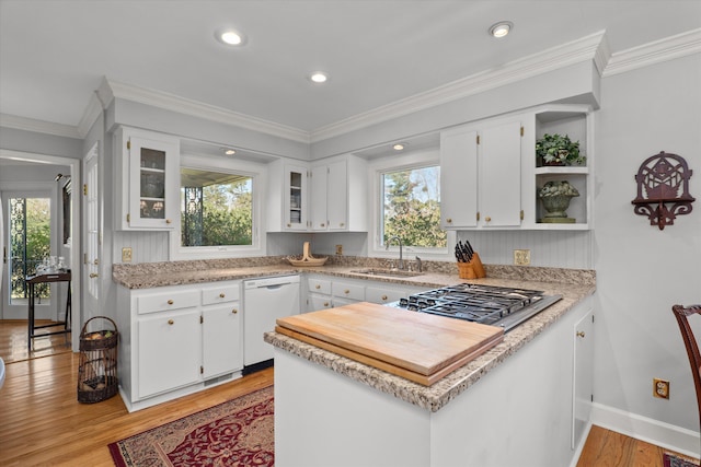 kitchen with a sink, stainless steel gas stovetop, white dishwasher, and light countertops