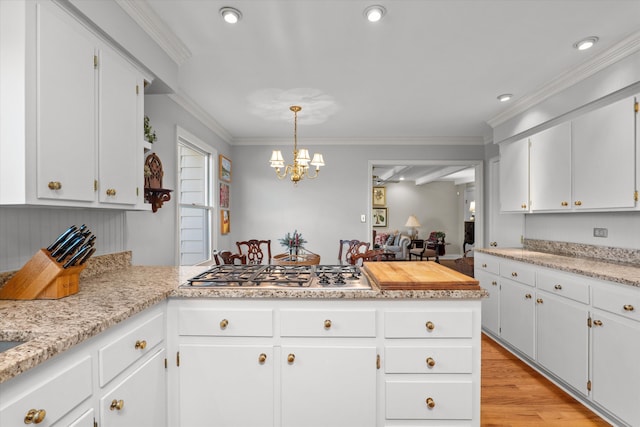 kitchen featuring crown molding, light countertops, a peninsula, stainless steel gas stovetop, and white cabinetry