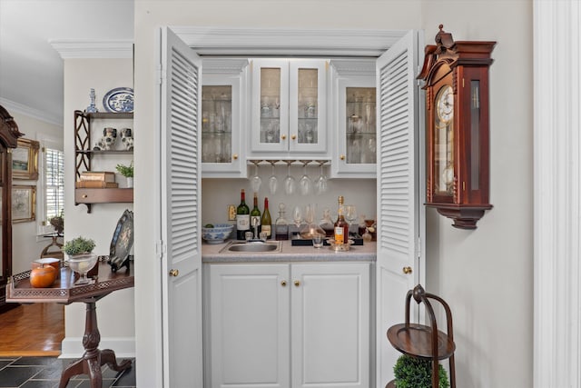 bar featuring crown molding, a dry bar, baseboards, and a sink