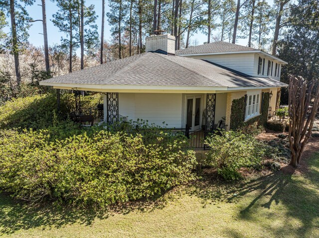 view of front facade with a shingled roof, french doors, and a chimney