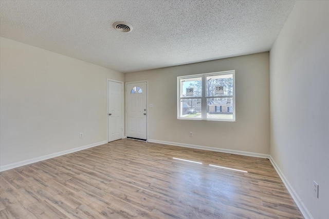 interior space with visible vents, a textured ceiling, baseboards, and wood finished floors