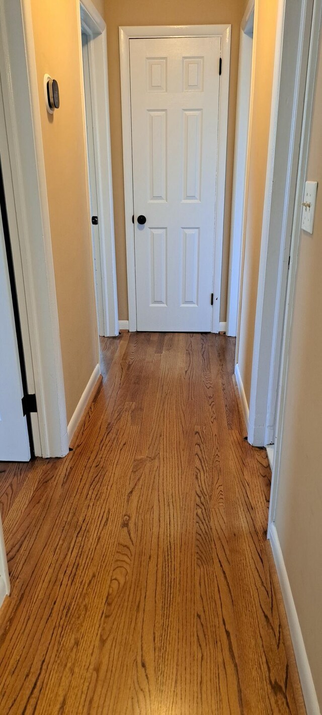 corridor featuring light wood-style flooring and baseboards