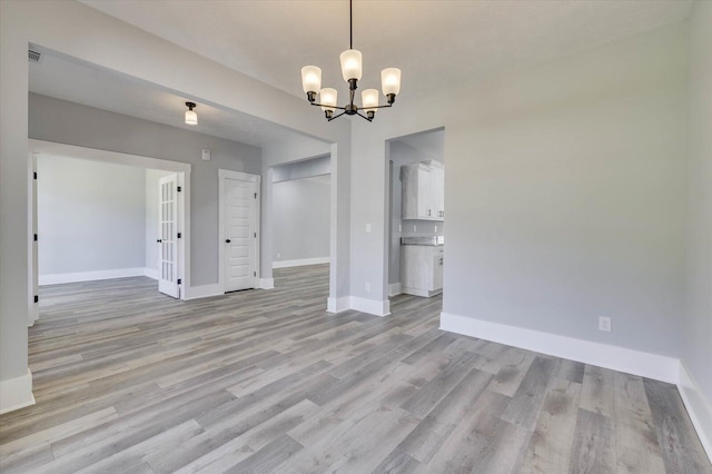 unfurnished dining area with light hardwood / wood-style floors and a notable chandelier