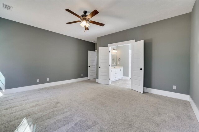 unfurnished bedroom featuring light carpet, ensuite bath, and ceiling fan