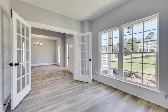 interior space with french doors, a chandelier, and light wood-type flooring