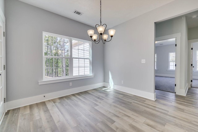 empty room with light hardwood / wood-style flooring and a chandelier