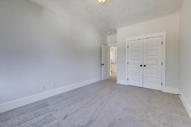 unfurnished bedroom with a textured ceiling, carpet floors, and a closet