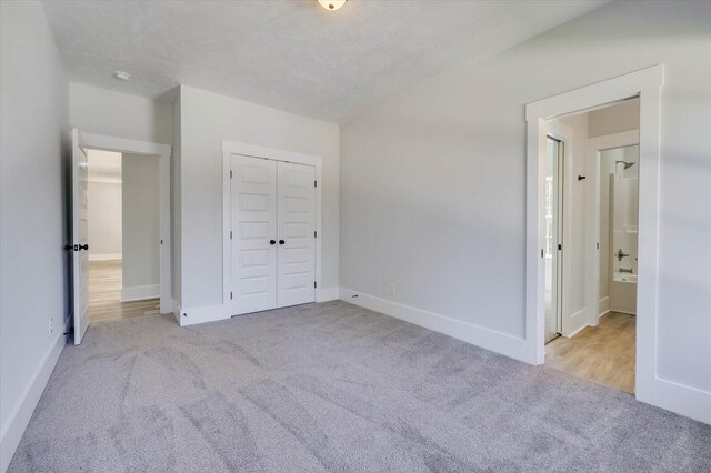 unfurnished bedroom featuring light carpet, a closet, and a textured ceiling