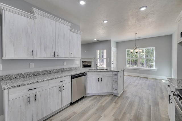 kitchen featuring light stone countertops, pendant lighting, a chandelier, and stainless steel dishwasher