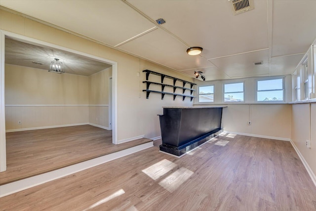 spare room featuring wood finished floors, visible vents, and baseboards