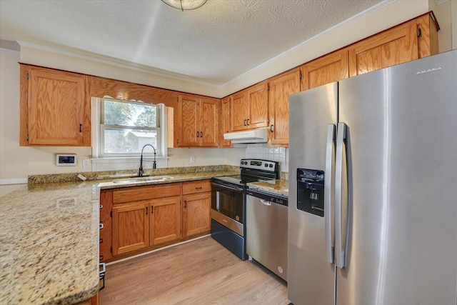 kitchen featuring stainless steel appliances, brown cabinetry, a sink, and under cabinet range hood