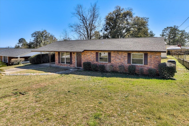 single story home featuring driveway, brick siding, an attached carport, fence, and a front yard