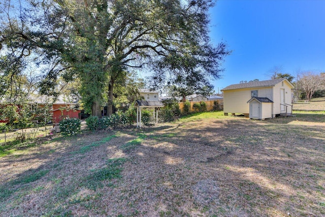 view of yard with an outdoor structure, a storage shed, and fence