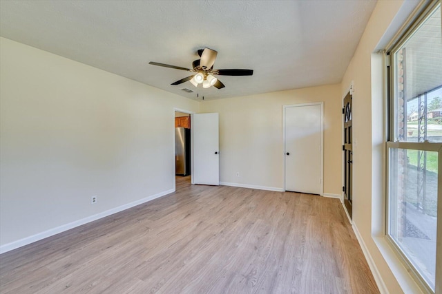 unfurnished bedroom with light wood finished floors, visible vents, baseboards, ceiling fan, and freestanding refrigerator