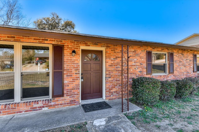 view of exterior entry featuring brick siding