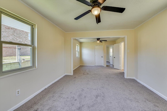 carpeted spare room featuring baseboards, ornamental molding, and a textured ceiling