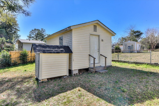 view of outdoor structure with entry steps, an outdoor structure, and a fenced backyard