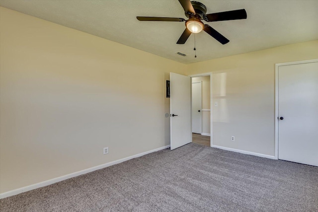 unfurnished bedroom featuring carpet flooring, ceiling fan, visible vents, and baseboards