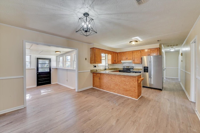 kitchen featuring appliances with stainless steel finishes, a peninsula, a textured ceiling, light wood-style floors, and a sink