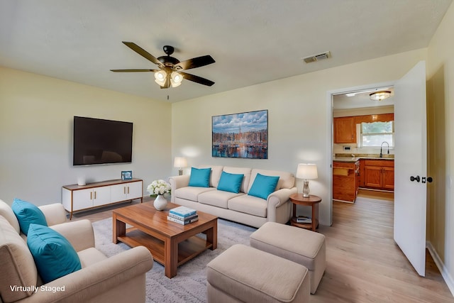 living area with a ceiling fan, visible vents, and light wood-style flooring