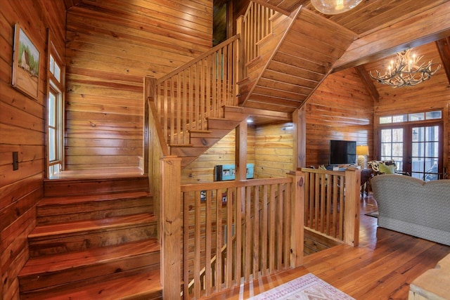 stairway with hardwood / wood-style flooring, wood ceiling, vaulted ceiling with beams, wood walls, and a notable chandelier