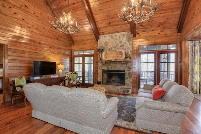 living area featuring a wealth of natural light, a stone fireplace, hardwood / wood-style floors, and an inviting chandelier