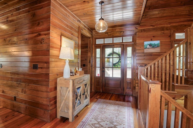 foyer featuring wood ceiling, wooden walls, hardwood / wood-style floors, and stairs