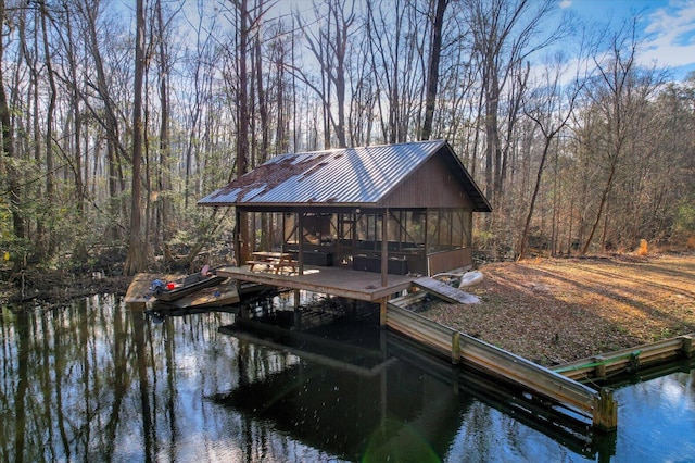 dock area with a water view, boat lift, and a wooded view