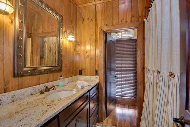 bathroom featuring wooden walls, wood finished floors, and vanity