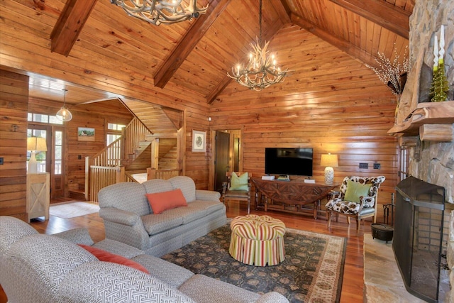 living room featuring a chandelier, a fireplace, wood finished floors, stairway, and beam ceiling